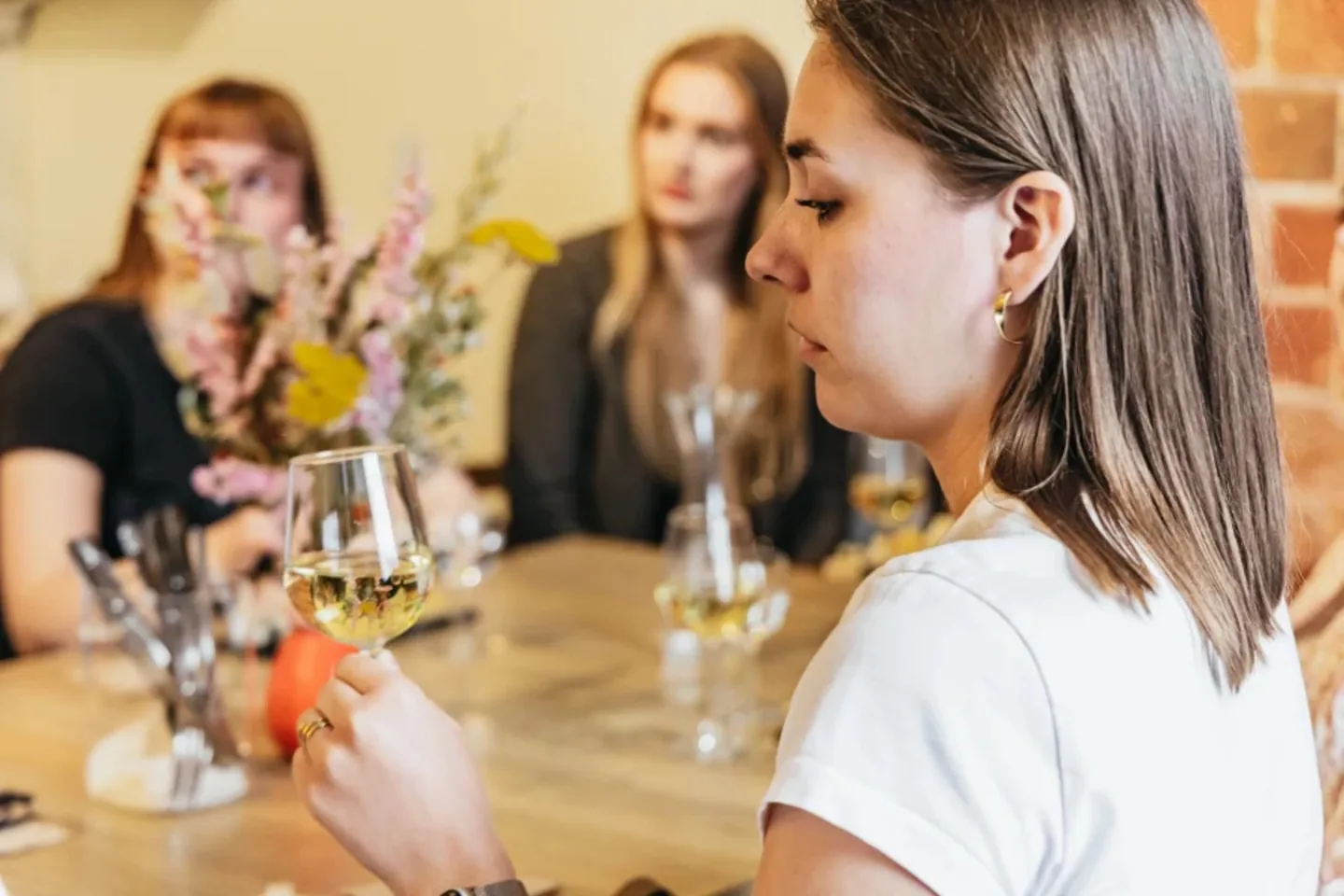 Participante qui goûte un vin pendant une Masterclass, planches et verres sur la table